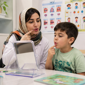 تمرین تلفظ و حرکات دهانی با آینه در جلسه گفتاردرمانی کودک در مرکز ماهان تهران